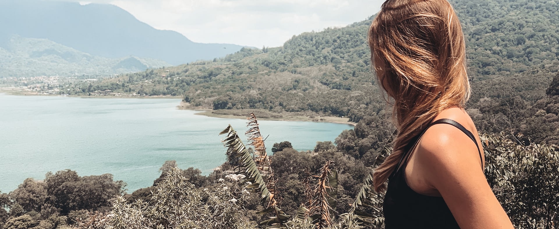 Sarah, Gründerin von Seelenkonferenz, steht auf einem Berg und schaut auf das Meer hinab, Sie schaut bewusst auf die Grenzen zwischen Wasser und Land